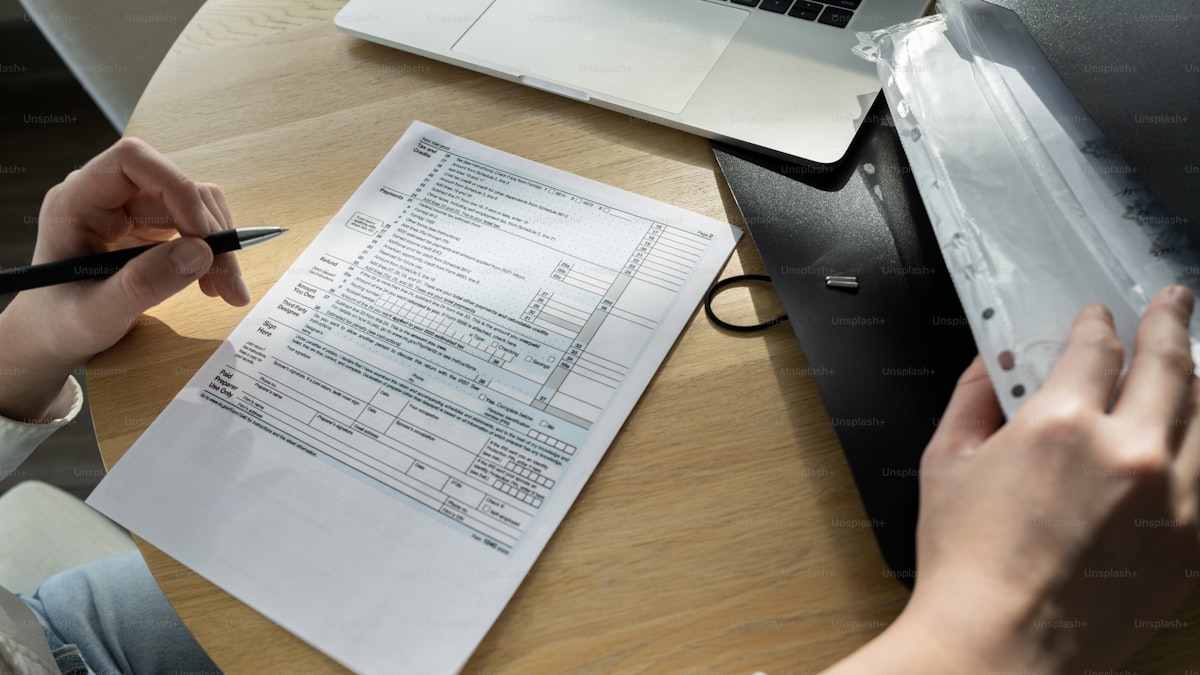 Persona sentada en escritorio con laptop y papeles dispersos